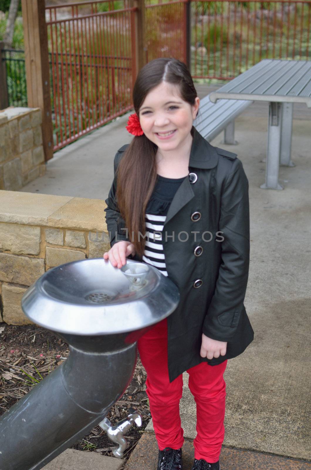 Young girl taking a drink of water in the playground