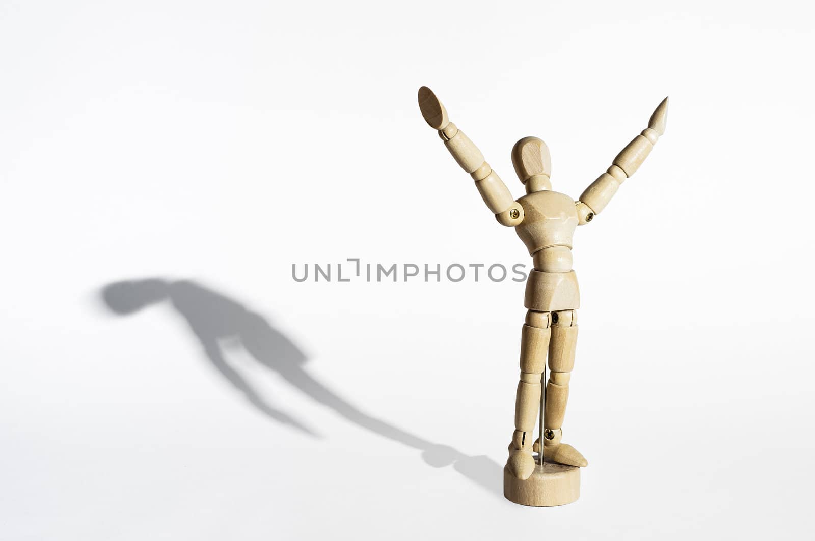 Happy wooden mannequin with sad shadow isolated in white background.