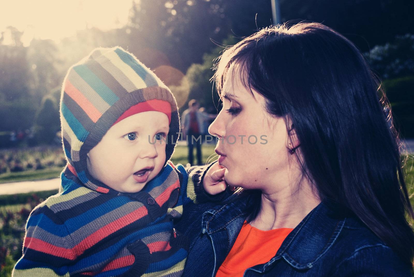 Mother and son walking on his hands in a sunny park. Soft Focus