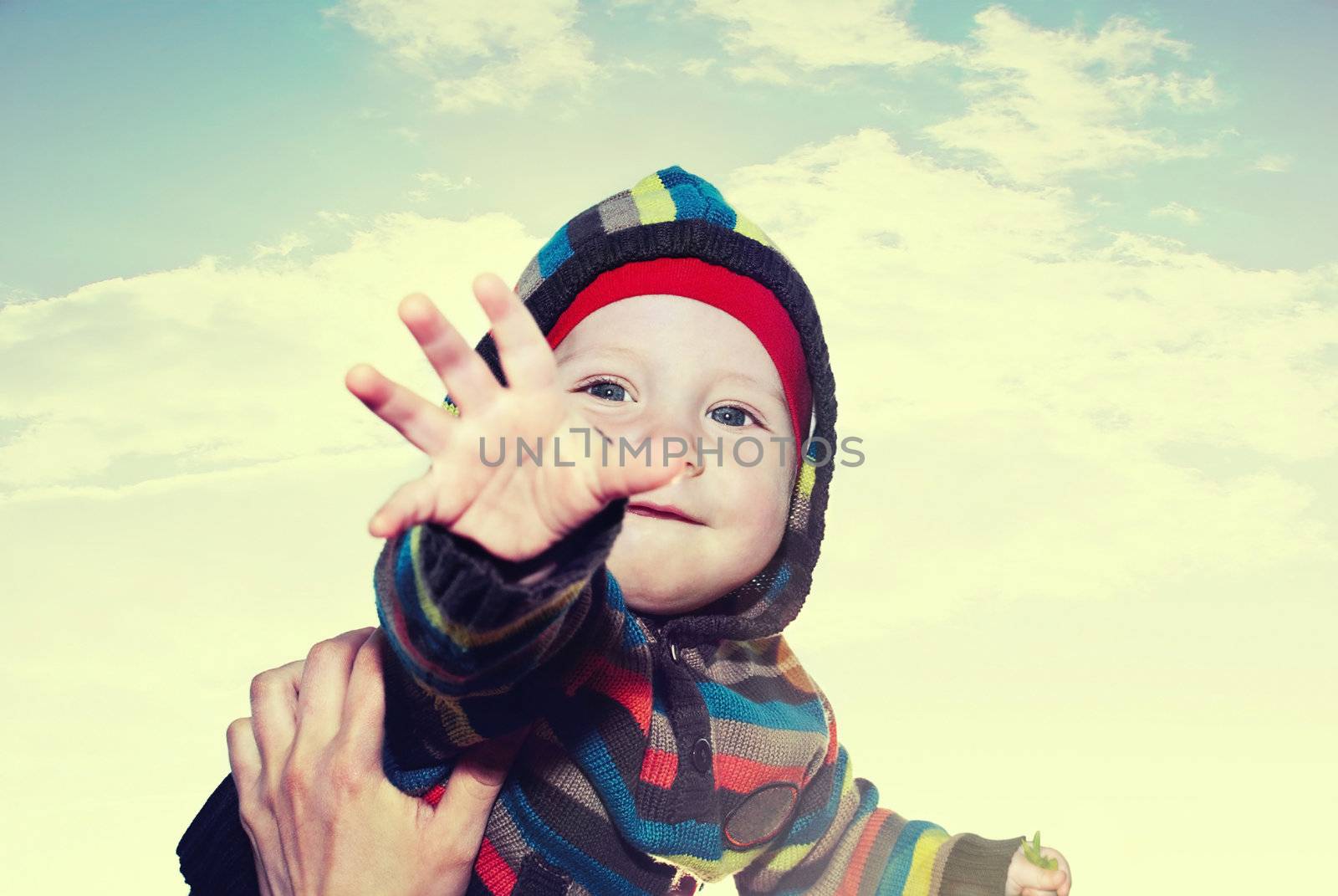 Happy boy on his hands at the mother to the sky with clouds.