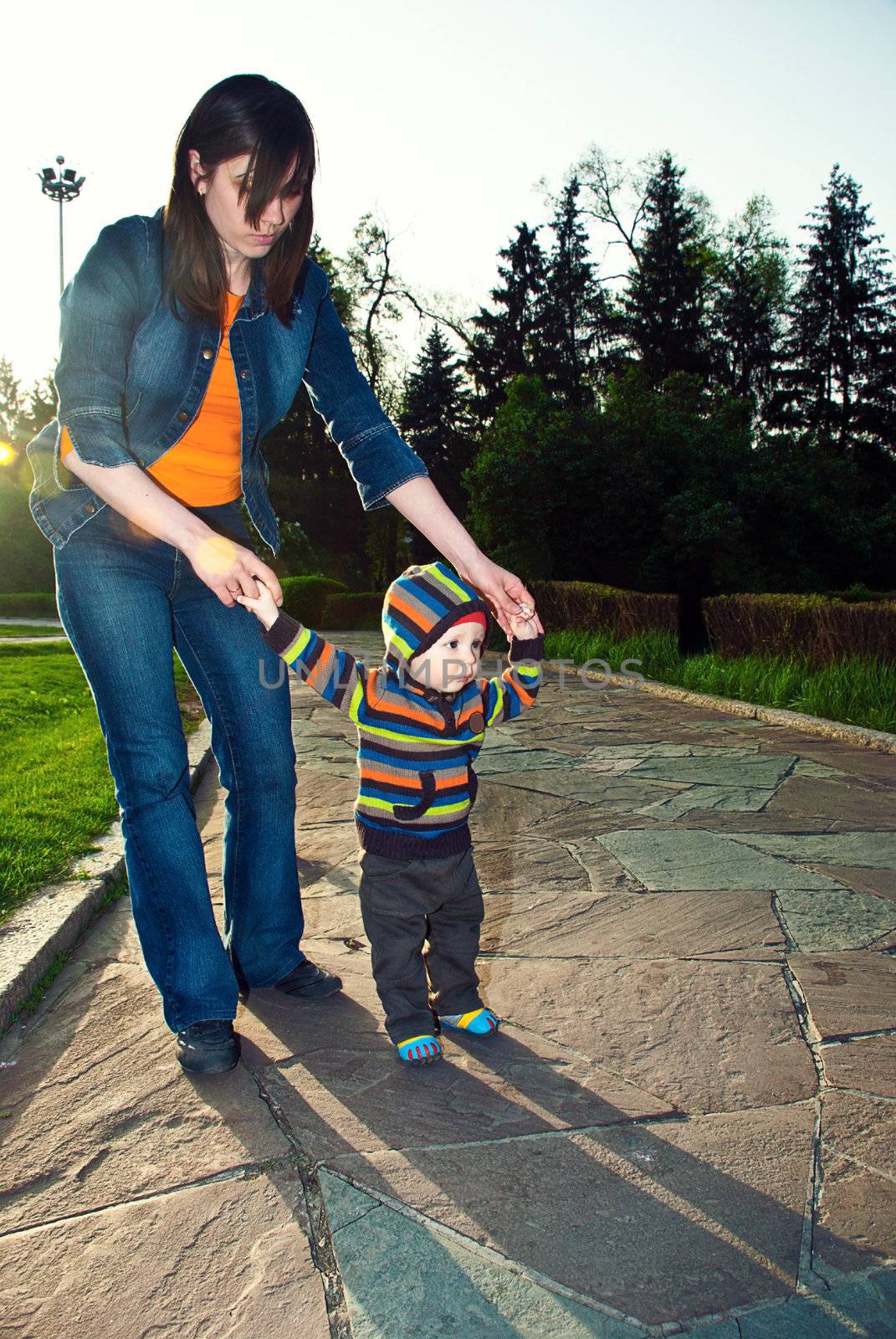 Happy young beautiful mother and her son have a walk in the park.