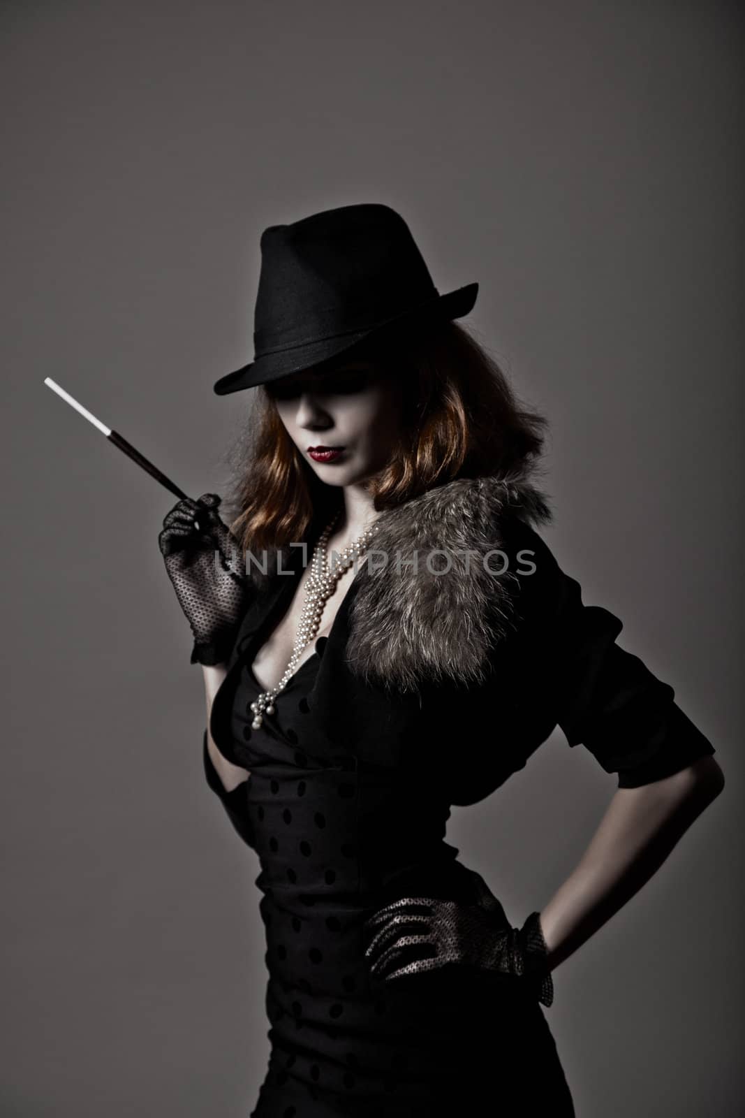 Retro shot of gangster woman in fedora hat and evening dress holding mouthpiece 