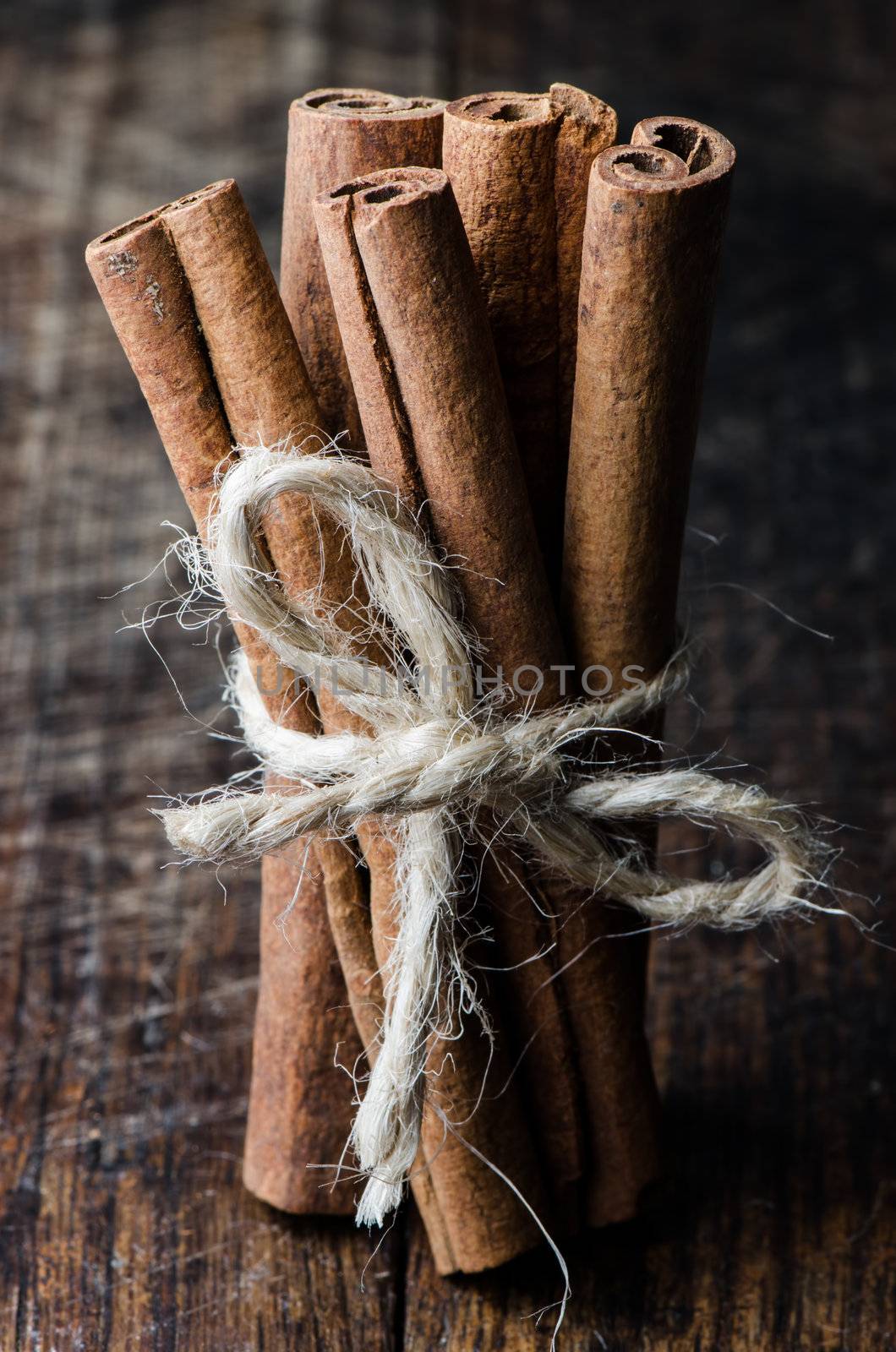 Close up tied by string bunch cinnamon sticks on dark wooden table