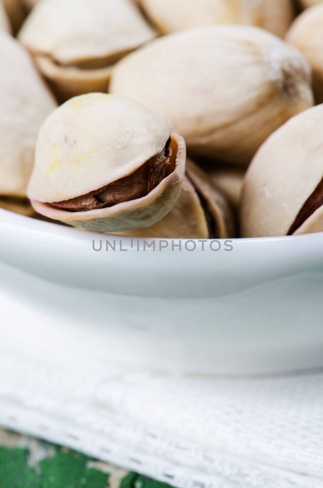 Close up pistachio in plate on white napkin on wooden table