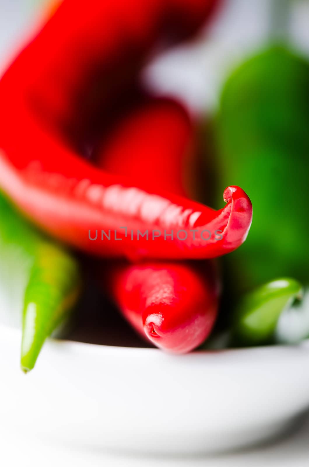 Green and red chili peppers in white bowl  by Nanisimova
