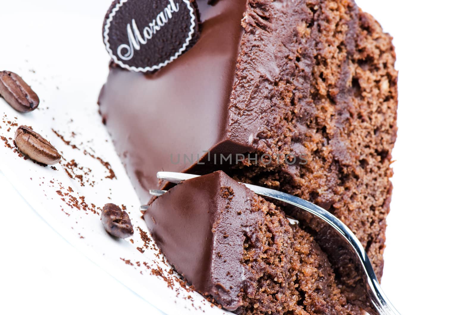 Piece of chocolate cake on white plate with coffee beans