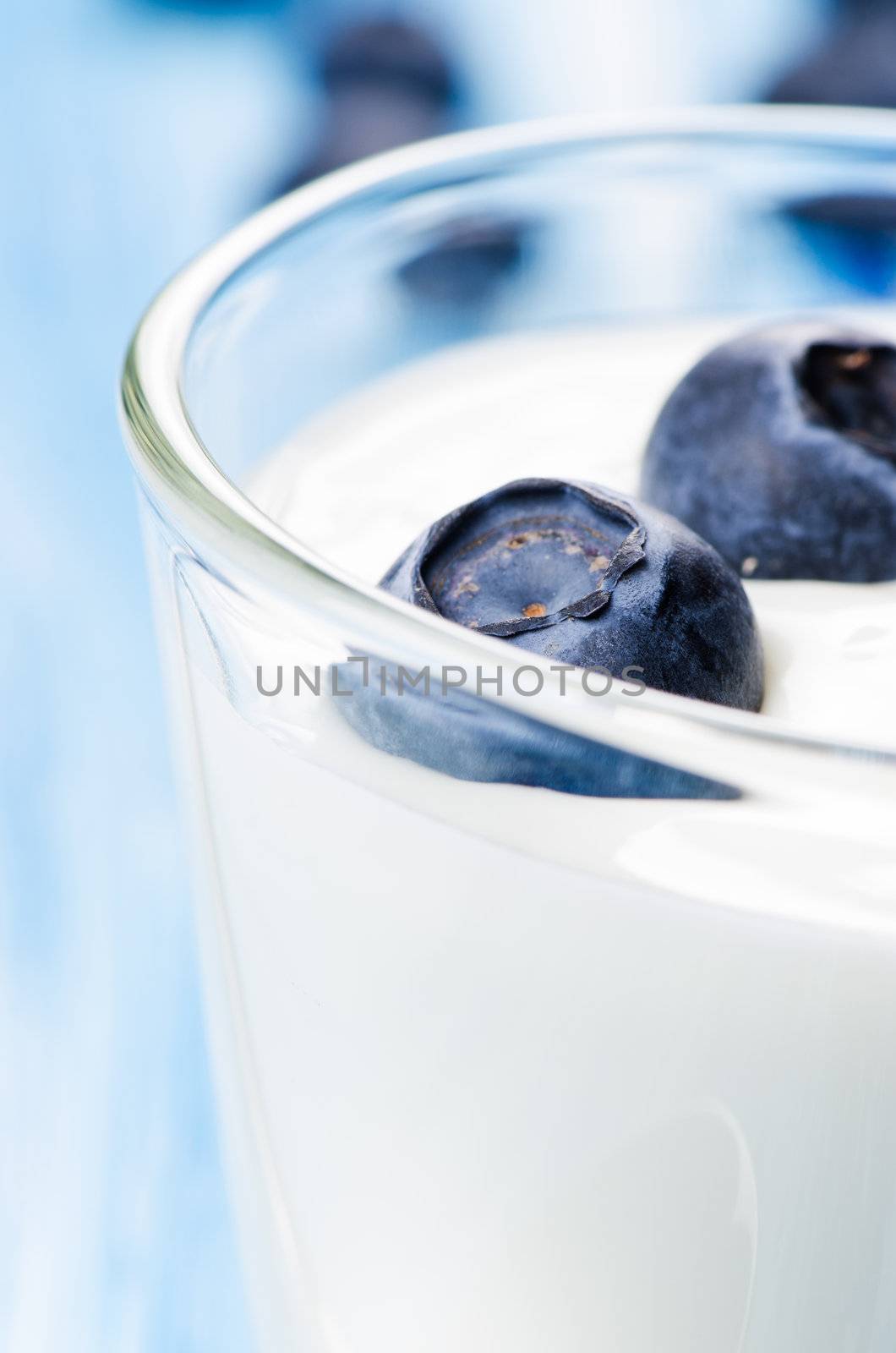 Blueberry yogurt on blue background close up