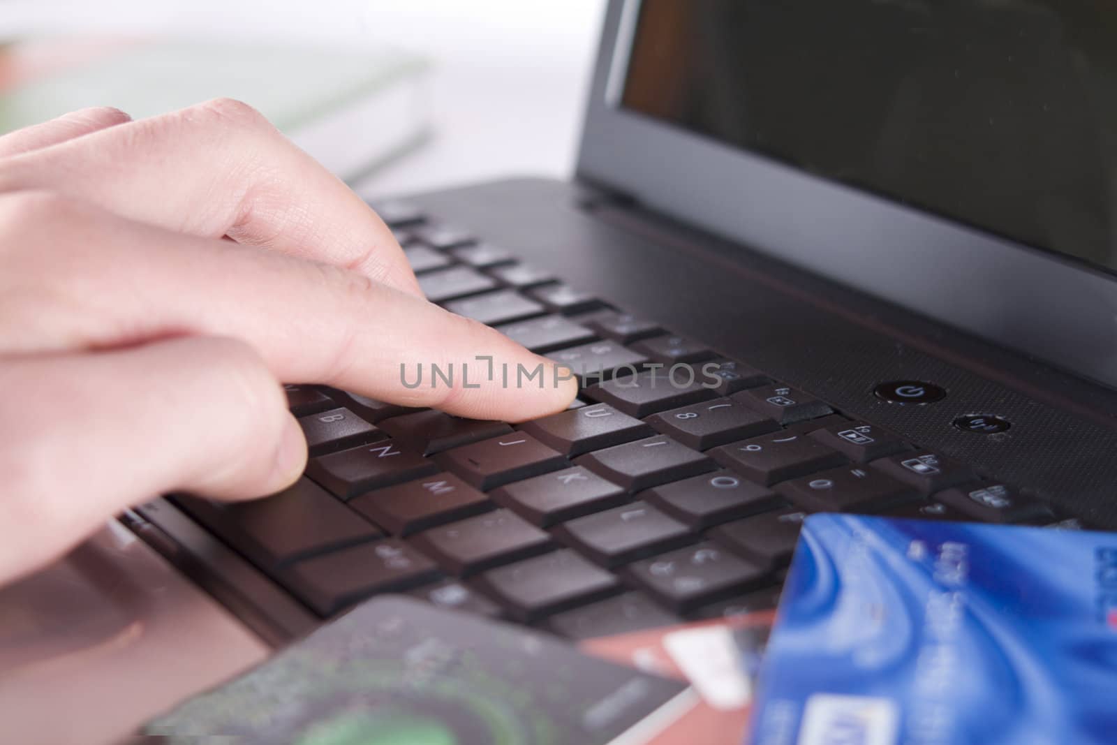 The hand works with the keyboard, in the foreground credit cards. Small depth of sharpness.
