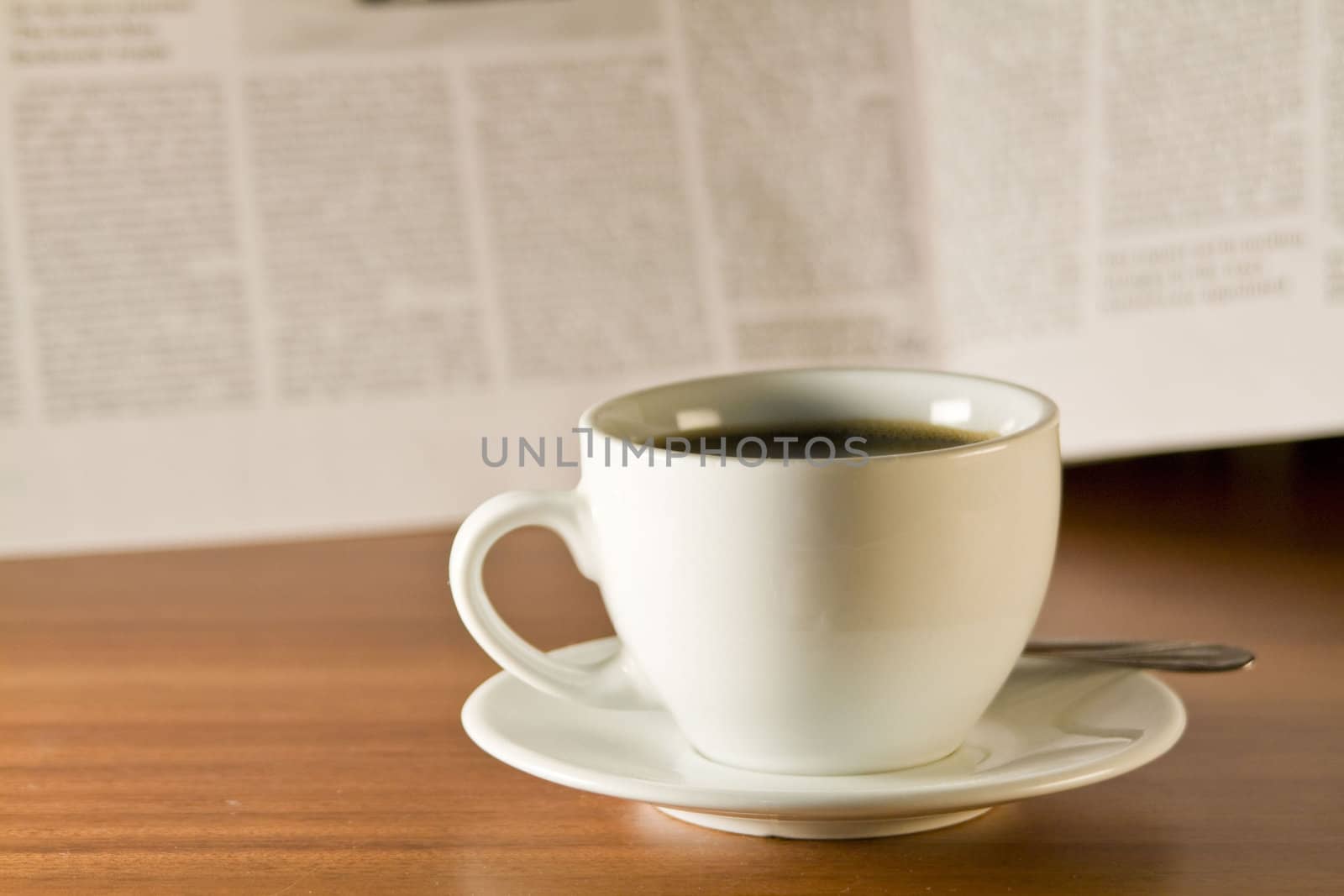 Coffee and newspaper on a wooden table. Small depth of sharpness.