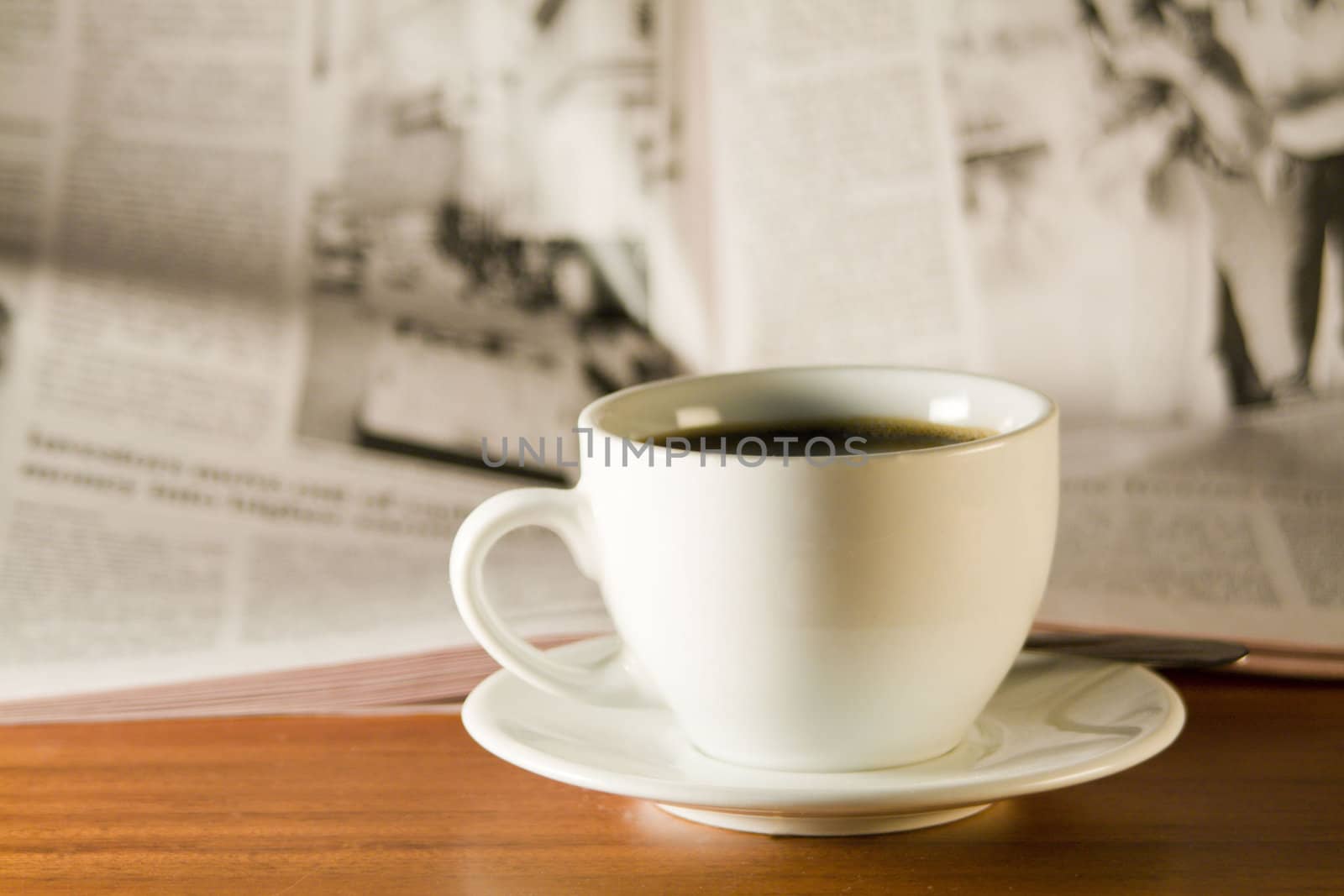 Coffee and newspaper on a wooden table. Small depth of sharpness..