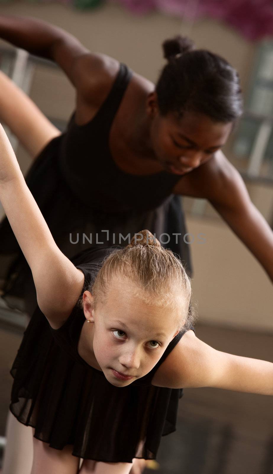 Two cute ballet pupils follow ballet instructions