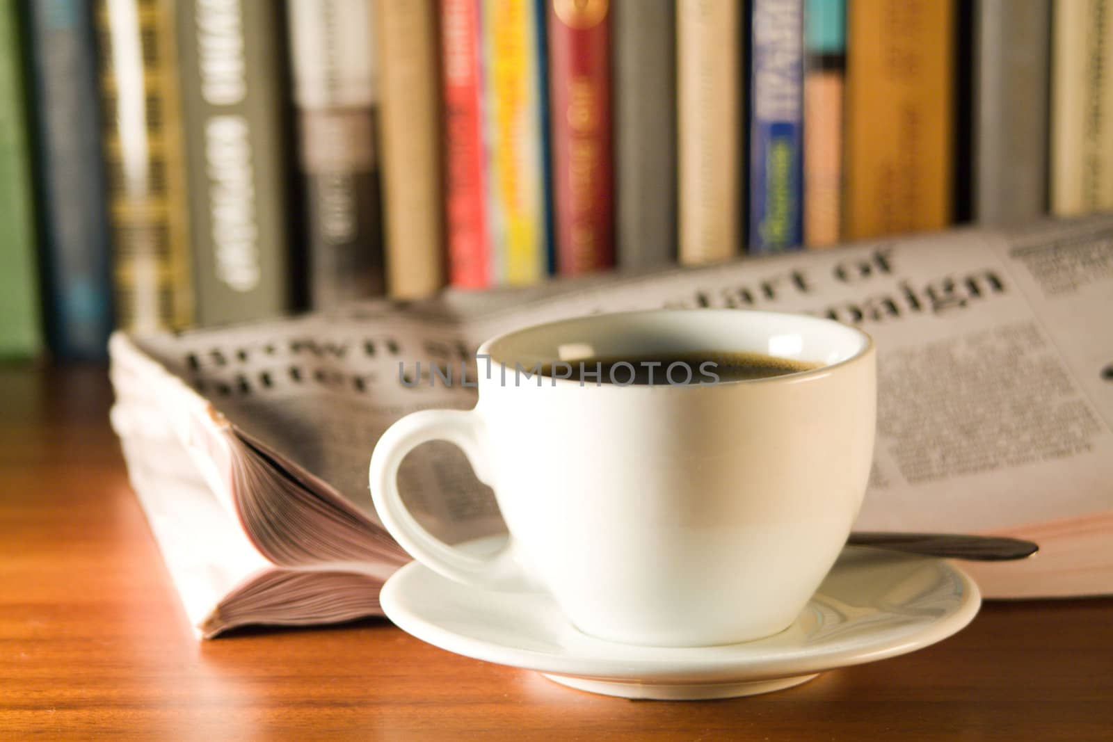 Coffee, newspaper and books on a wooden table. Small depth of sharpness.
