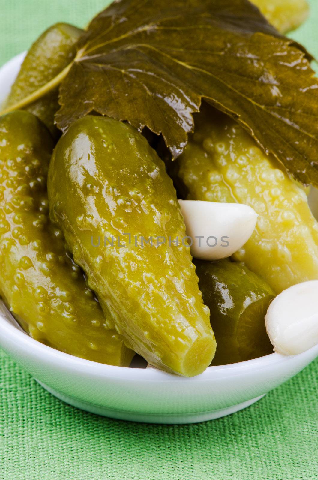 Pickles in bowl on green napkin close up