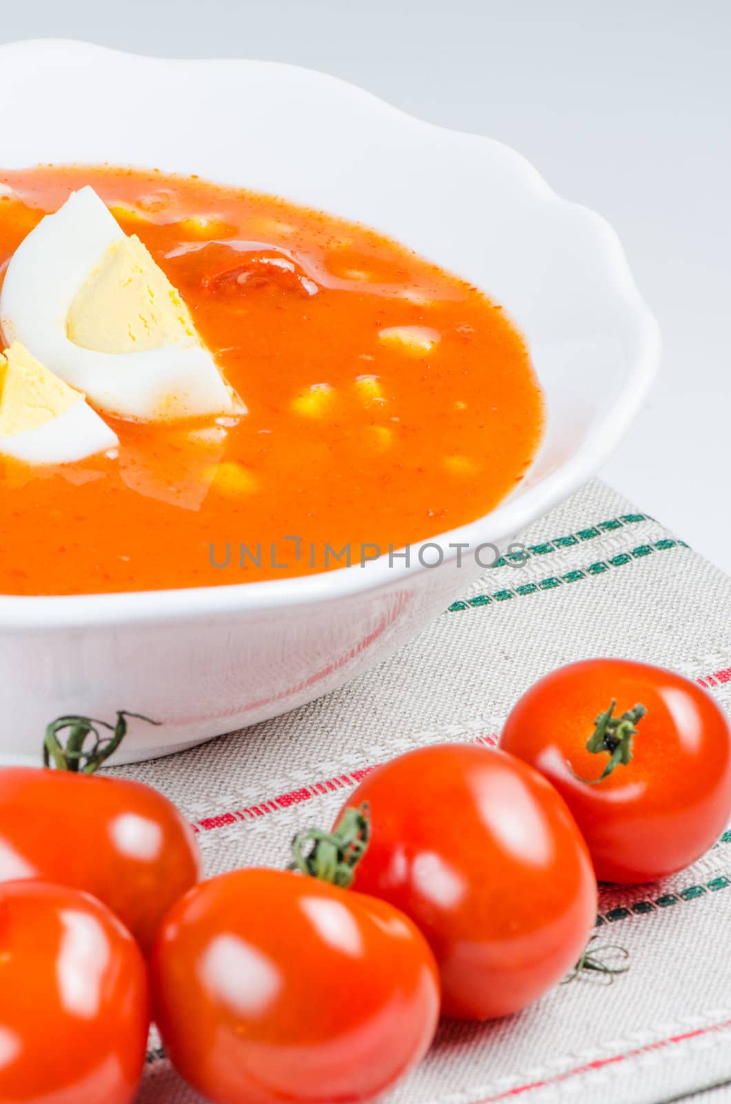 Tomato soup with eggs in white bowl on napkin close up