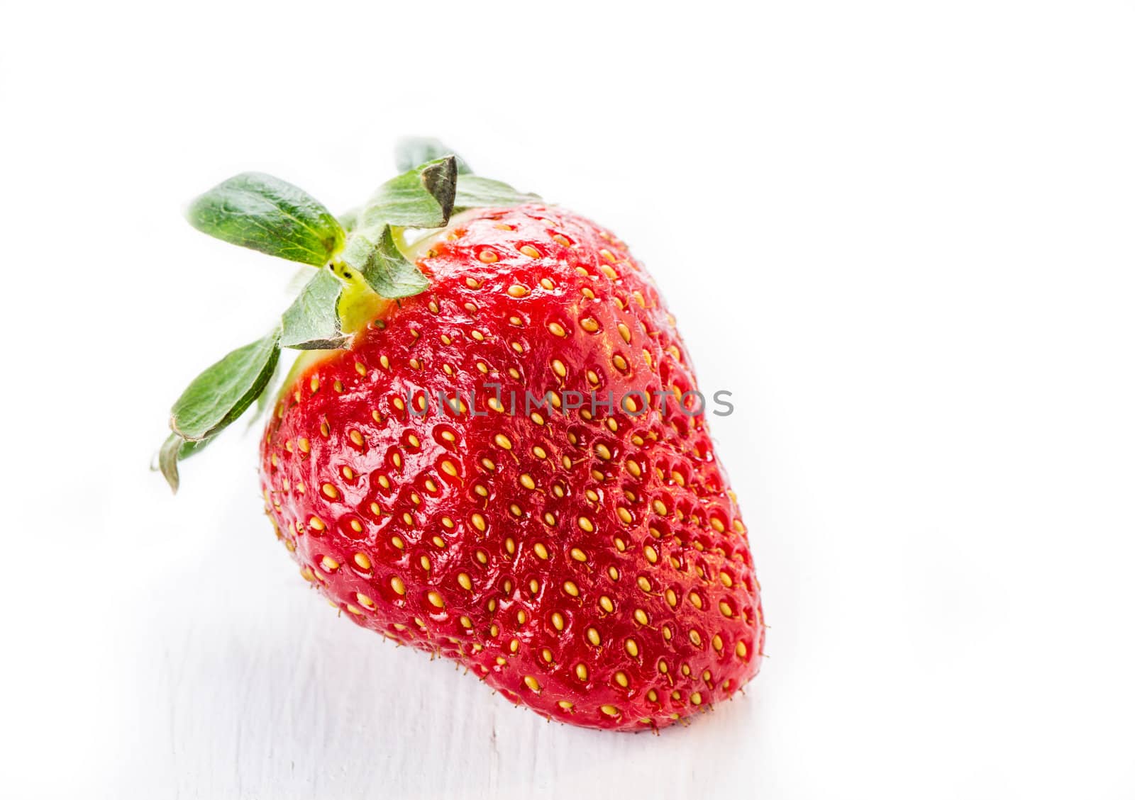 One strawberry on white wooden table