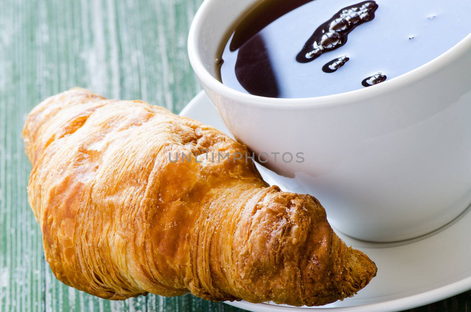 Cofee and croissant on green table by Nanisimova