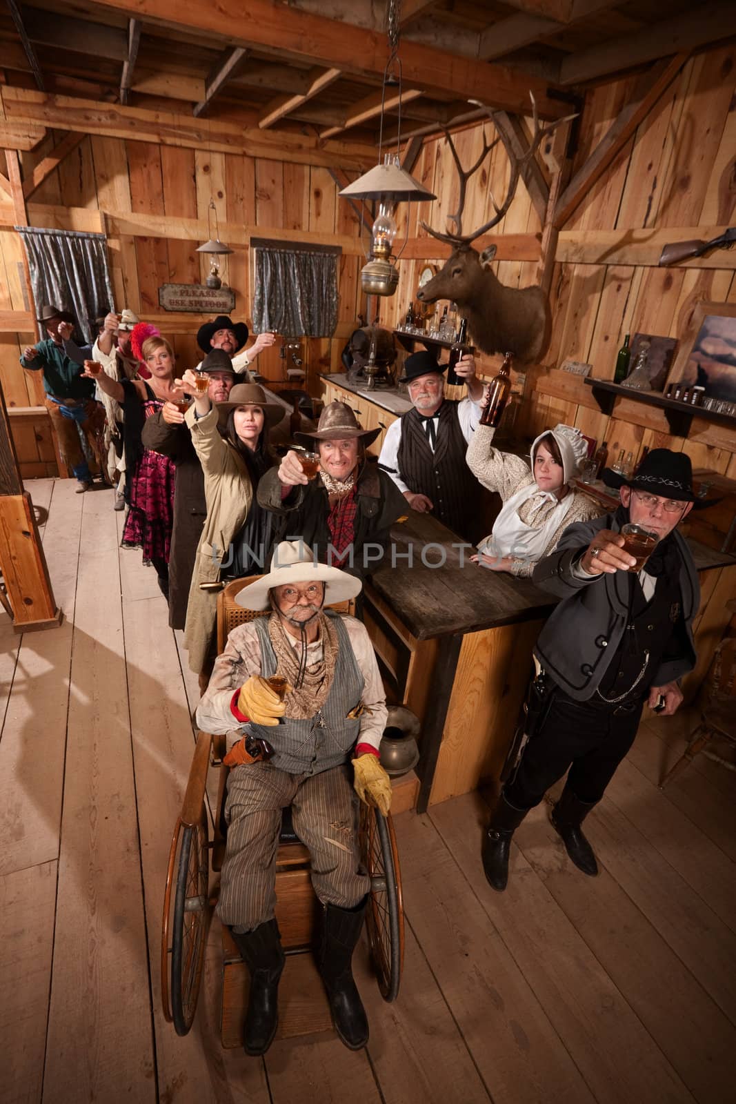 Large group of customers in old west saloon toasting with drinks