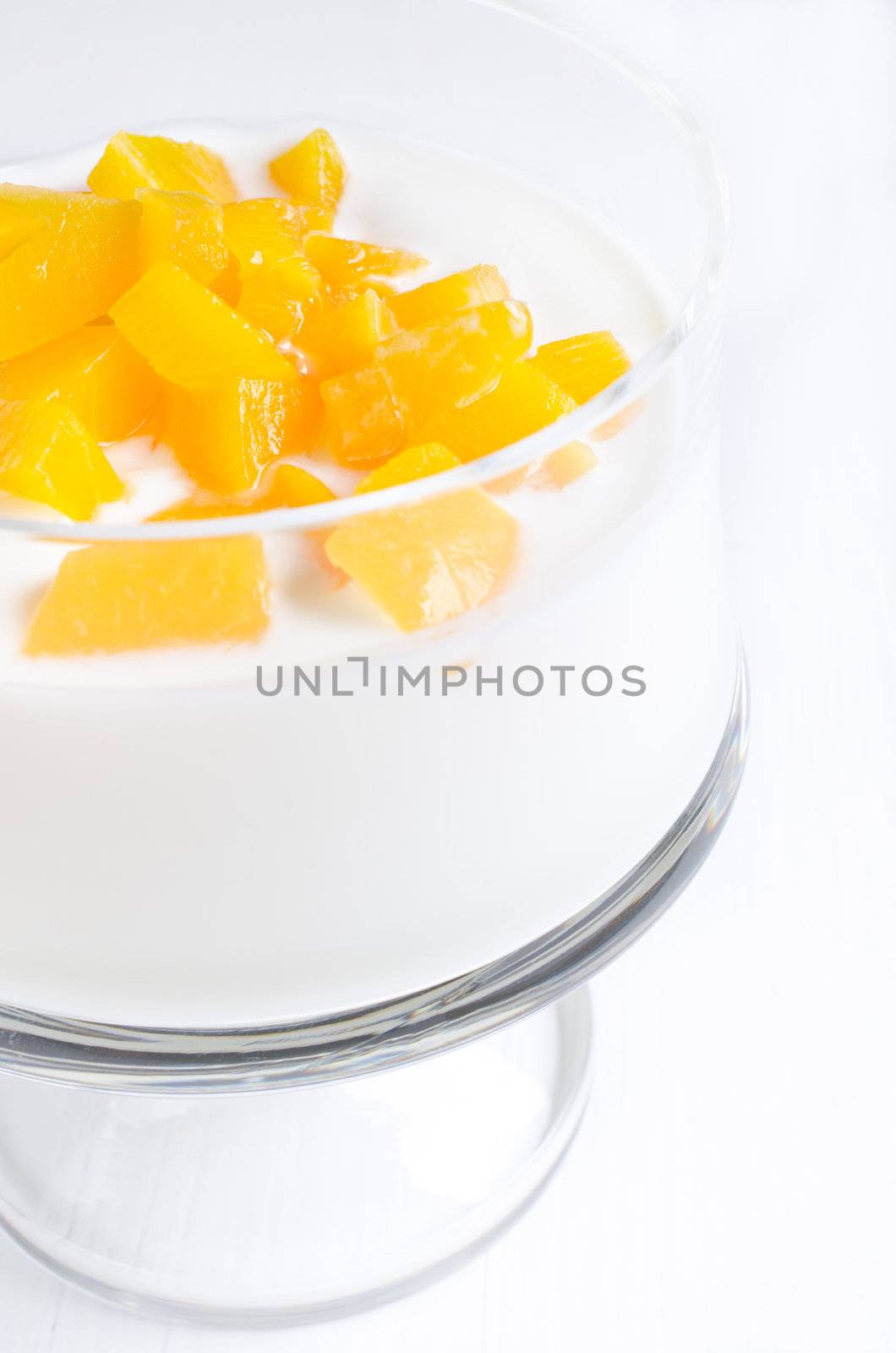 Yogurt with peach in glass bowl close up
