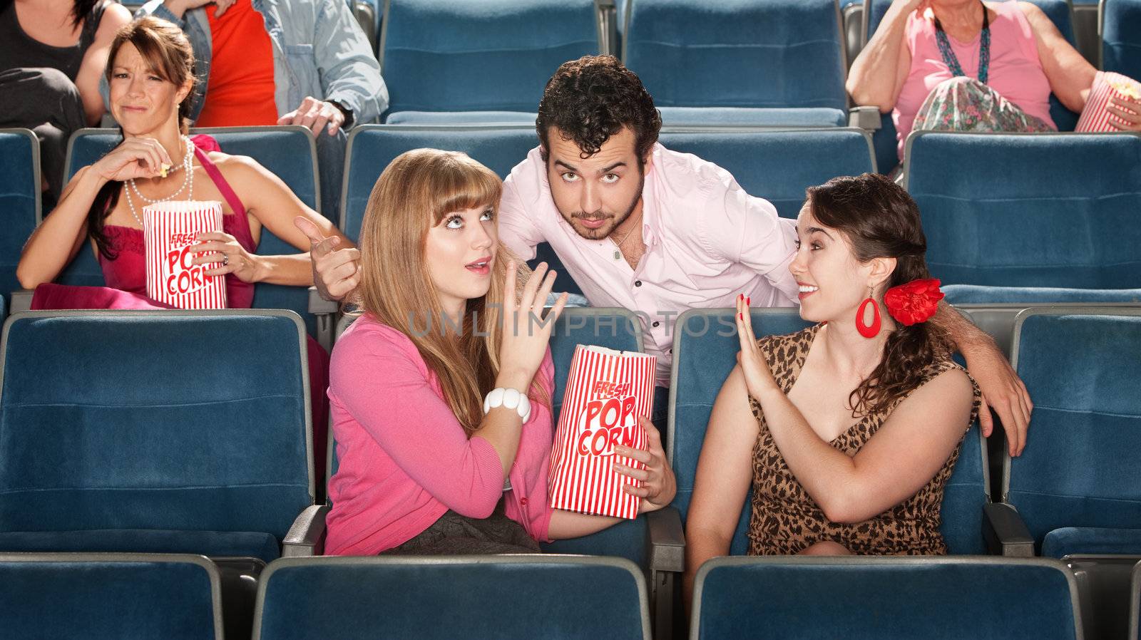 Flirtacious man with 2 young women in theater
