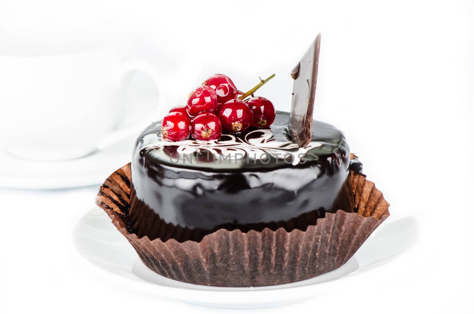 Chocolate cake with redcurrants on white cup background