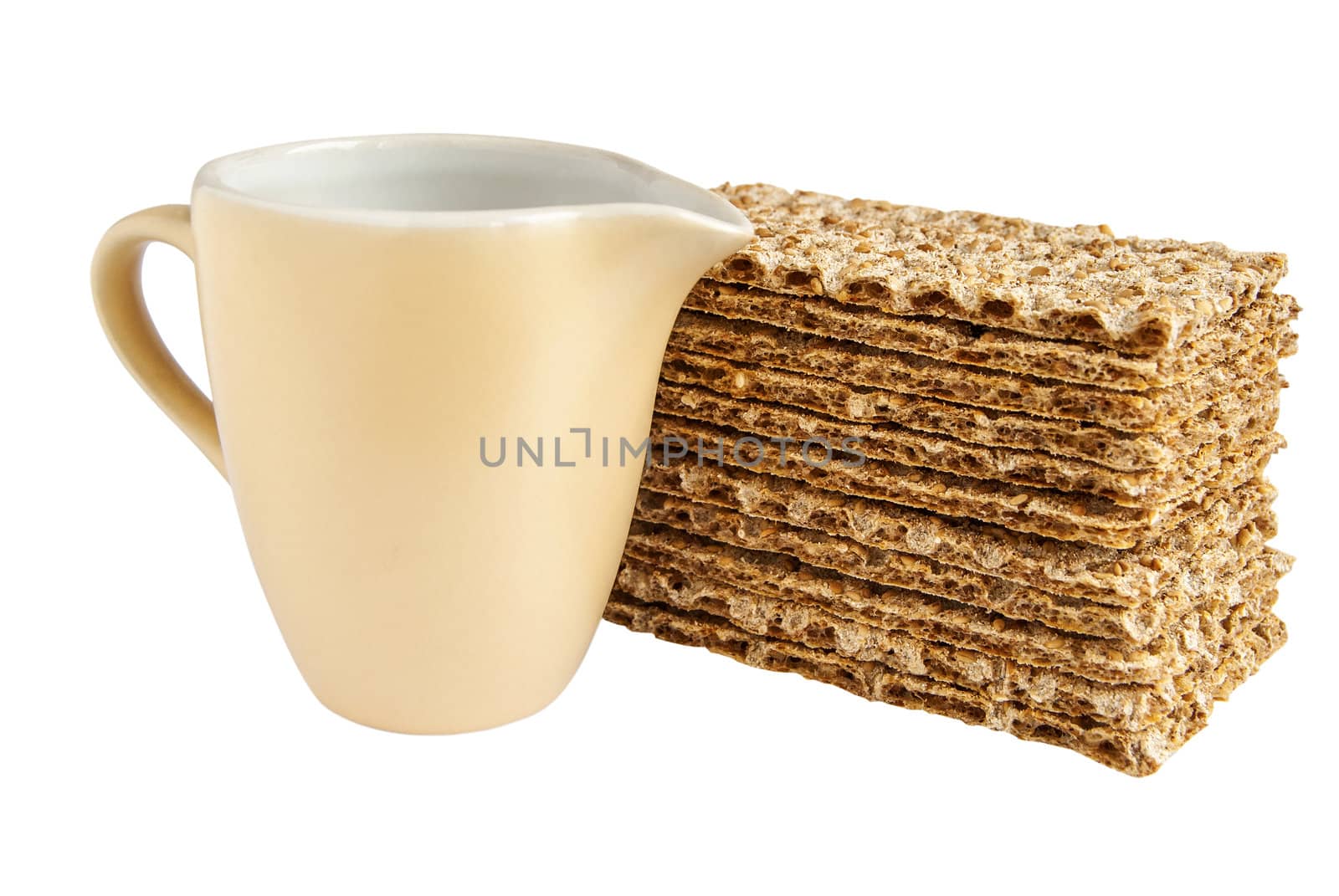 Milk jug and sesame wholegrain crispbreads isolated on white background