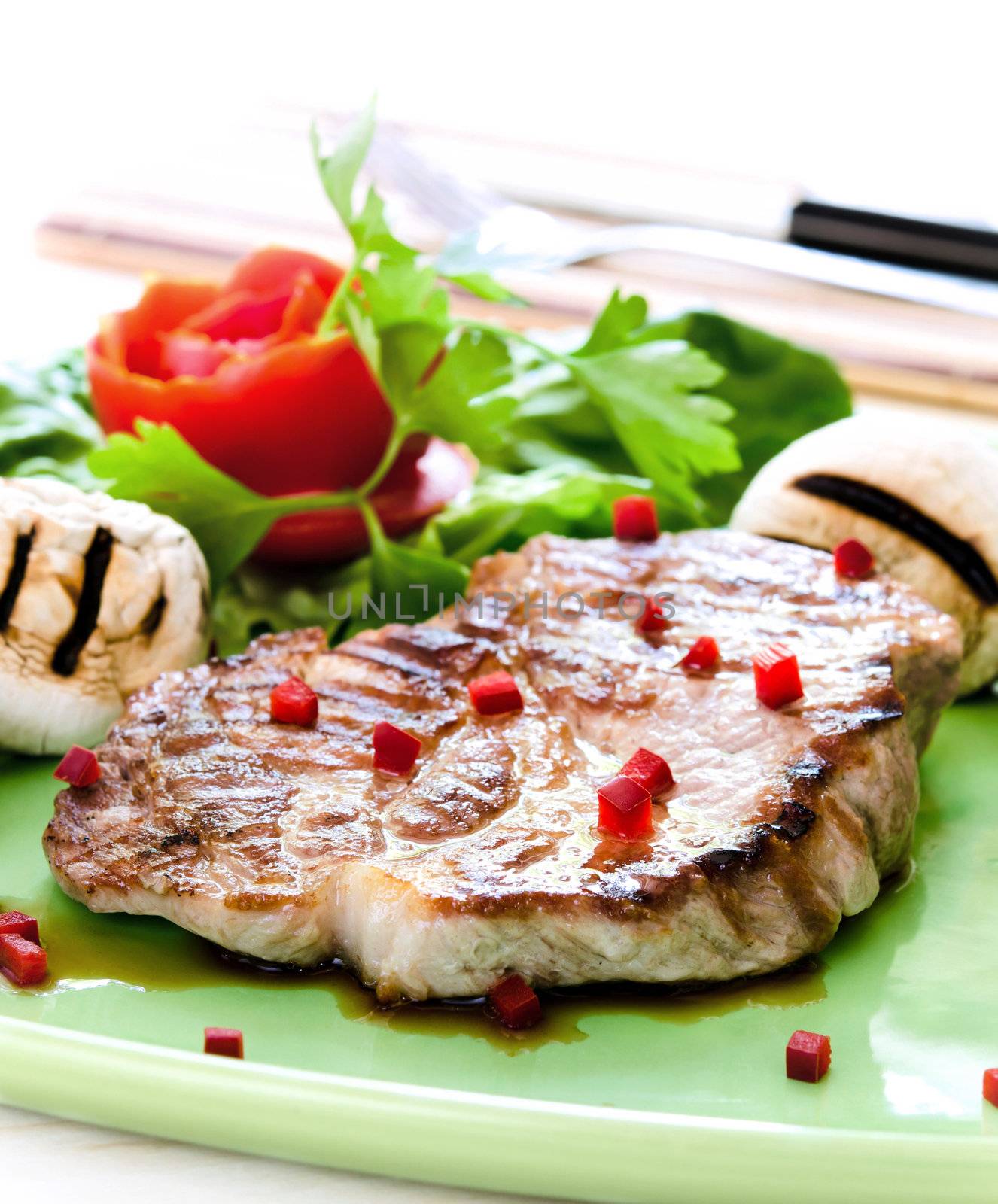 Pork steak with mushrooms and tomato rose on white background