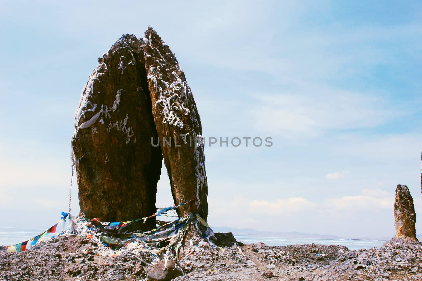Landscape of huge rocks wrapped with colorful prayer flags at a lakeside in Tibet