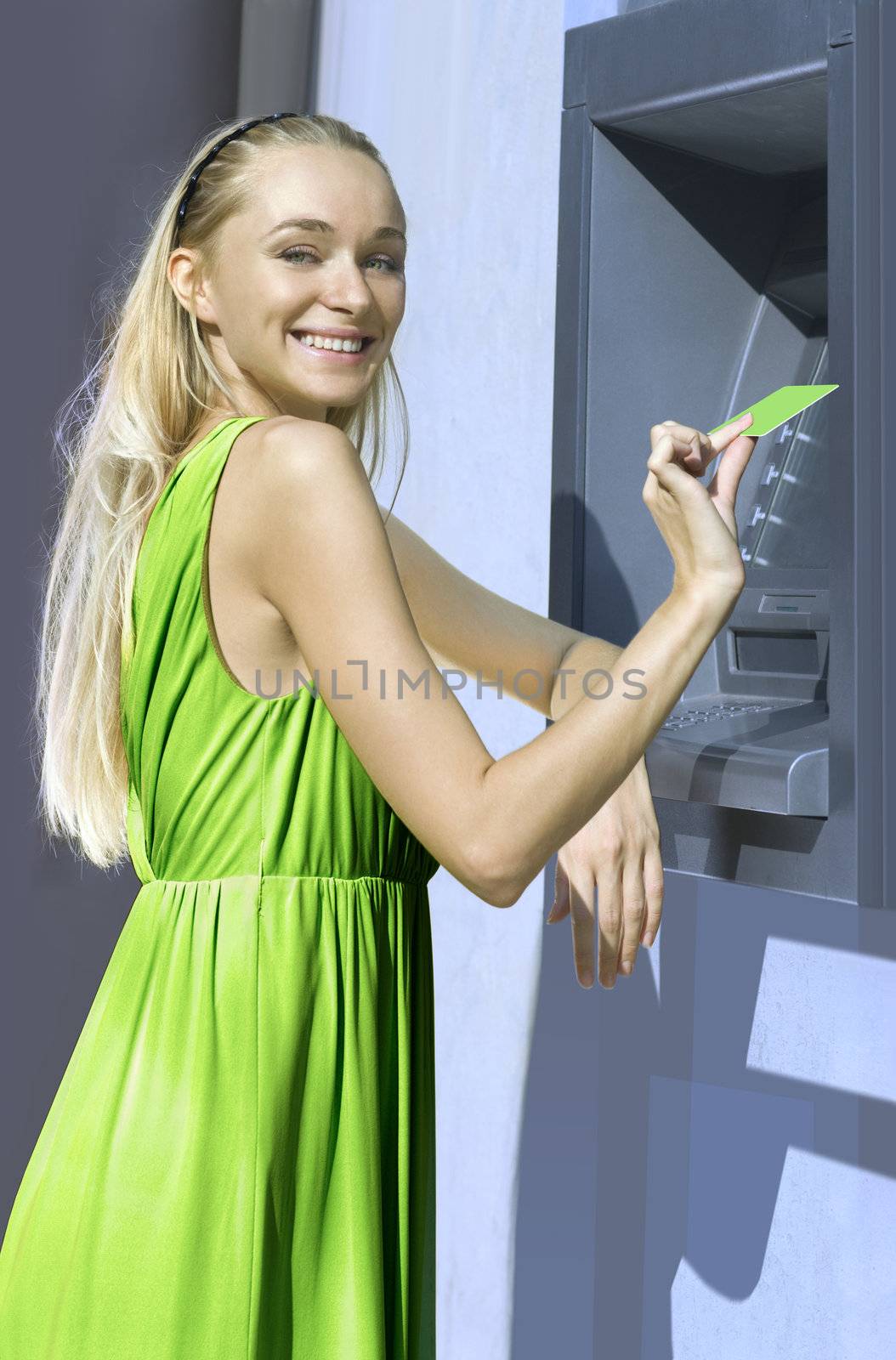 beautiful blond woman near a cash machine with plastic card