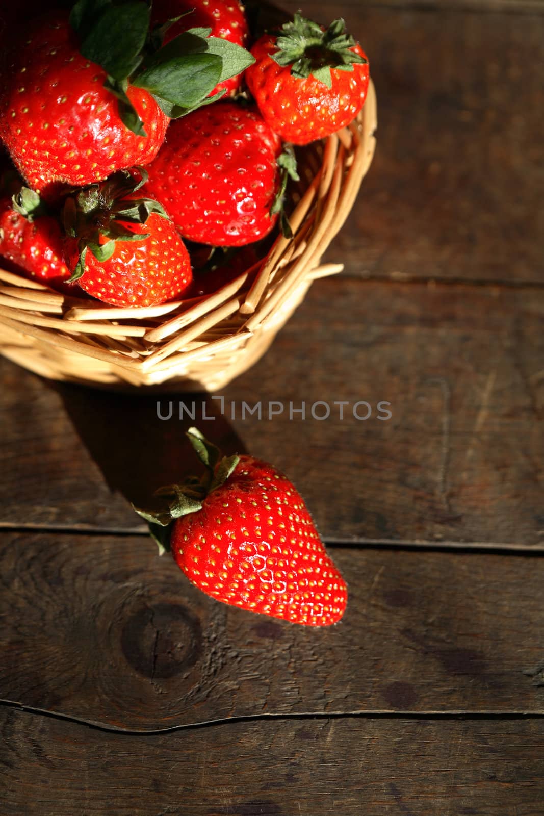 Still life with freshness red strawberry in wicker basket on old wooden surface