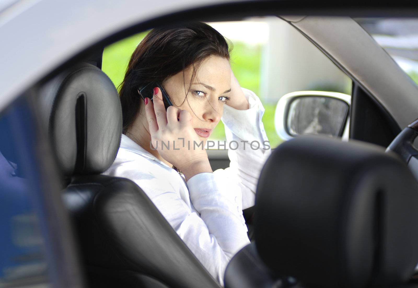 The business woman sits in the car and speaks by phone