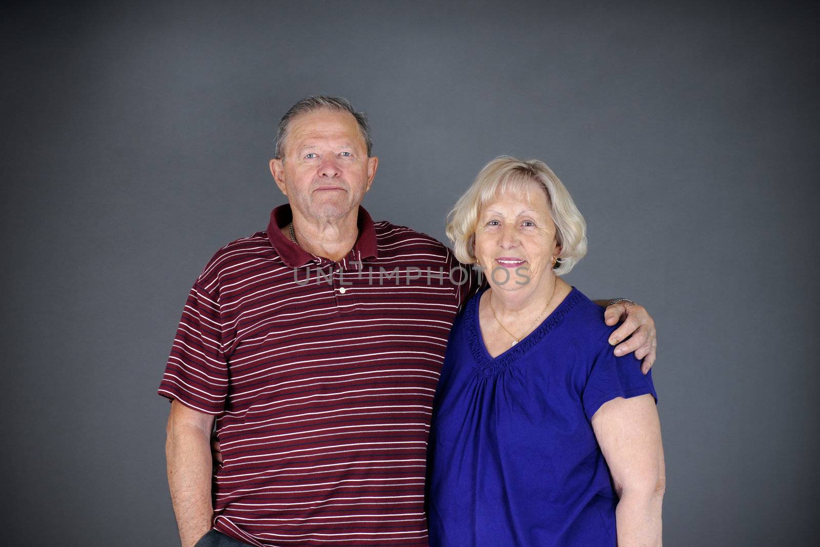 Happy and healthy senior couple looking at camera, studio shot over grey background.