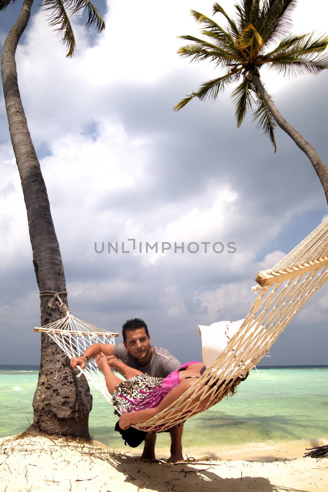 Handsome man chatting to woman in hammock by chrascina