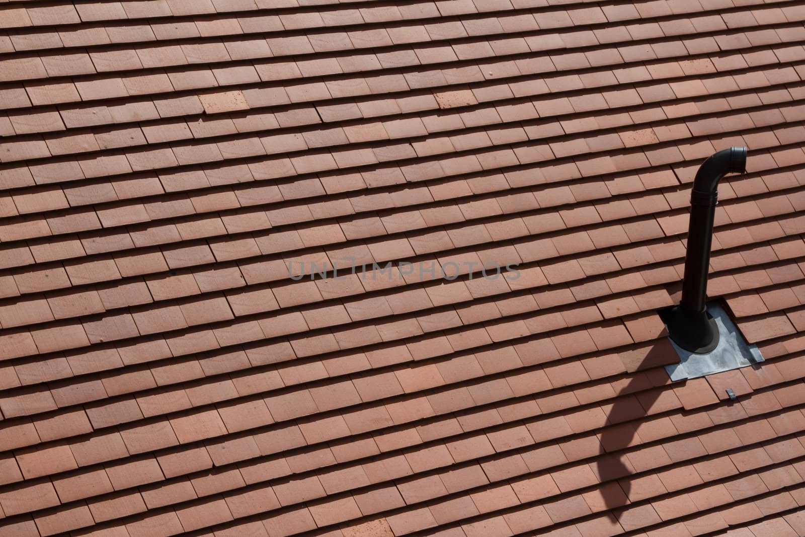 A new roof with red tiles and a ventilation pipe with rubber holding sleeve and a lead flashing.