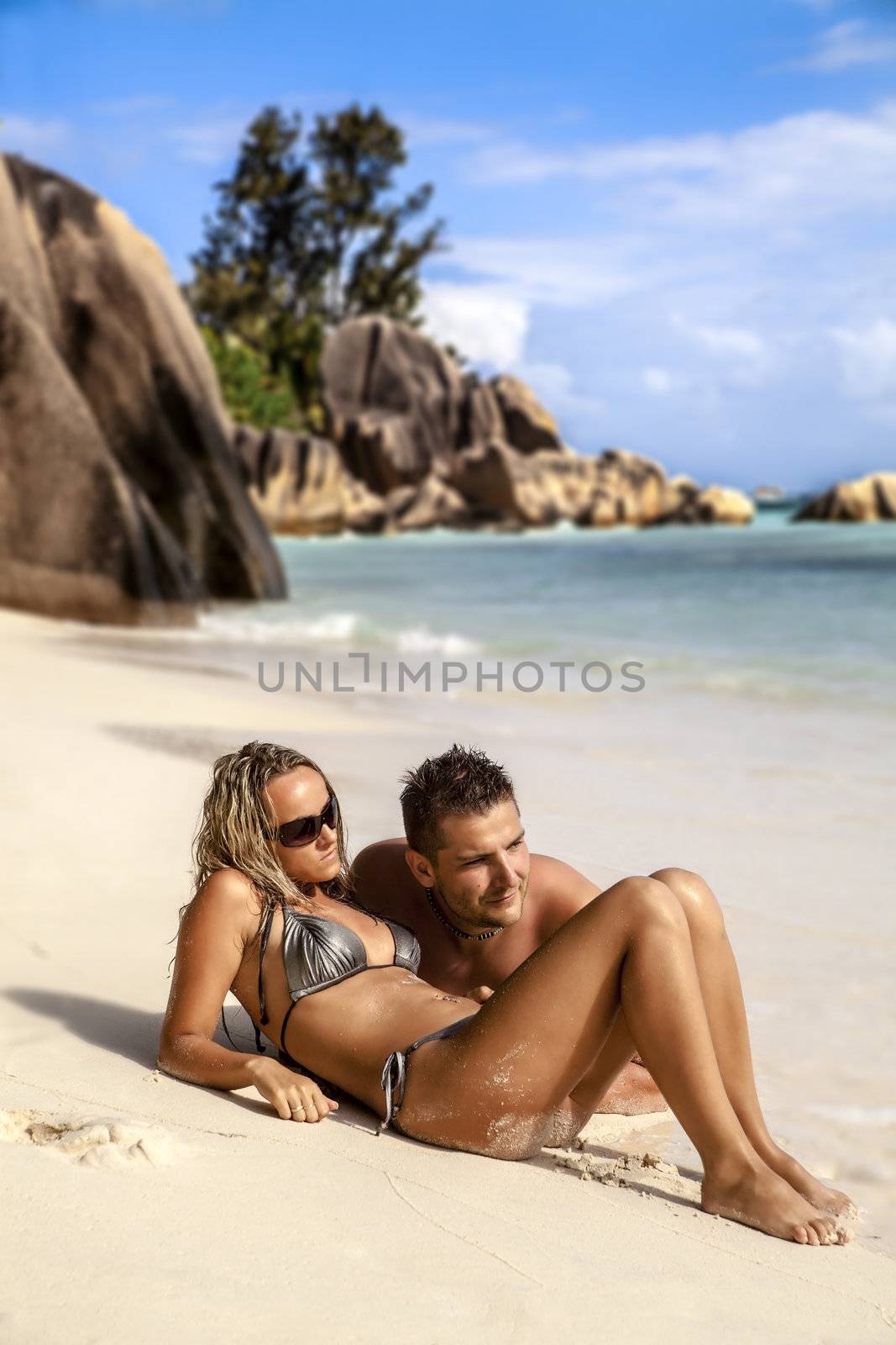 Romantic young couple lying on the beach in the sand enjoying the summer sunshine
