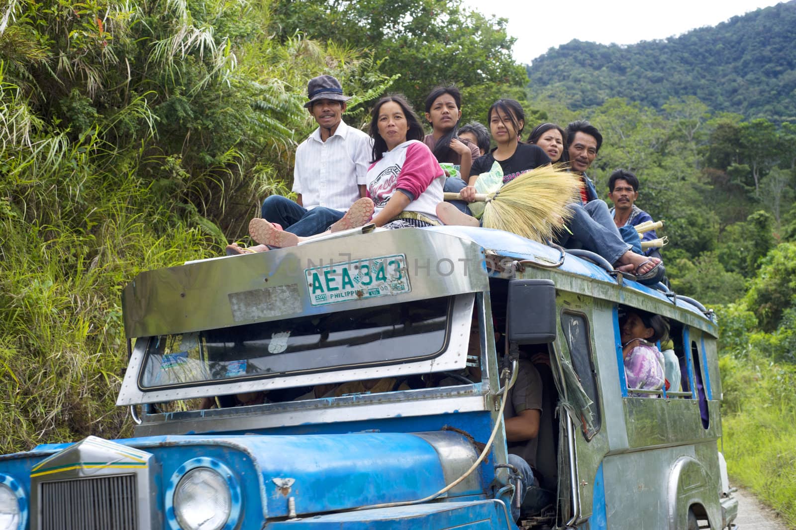 Bontoc, Philippines - March 26, 2012:  Passengers sit atop a very full jeepney The jeepney found everywhere in the country. It carries between 16 to 30 passengers.
