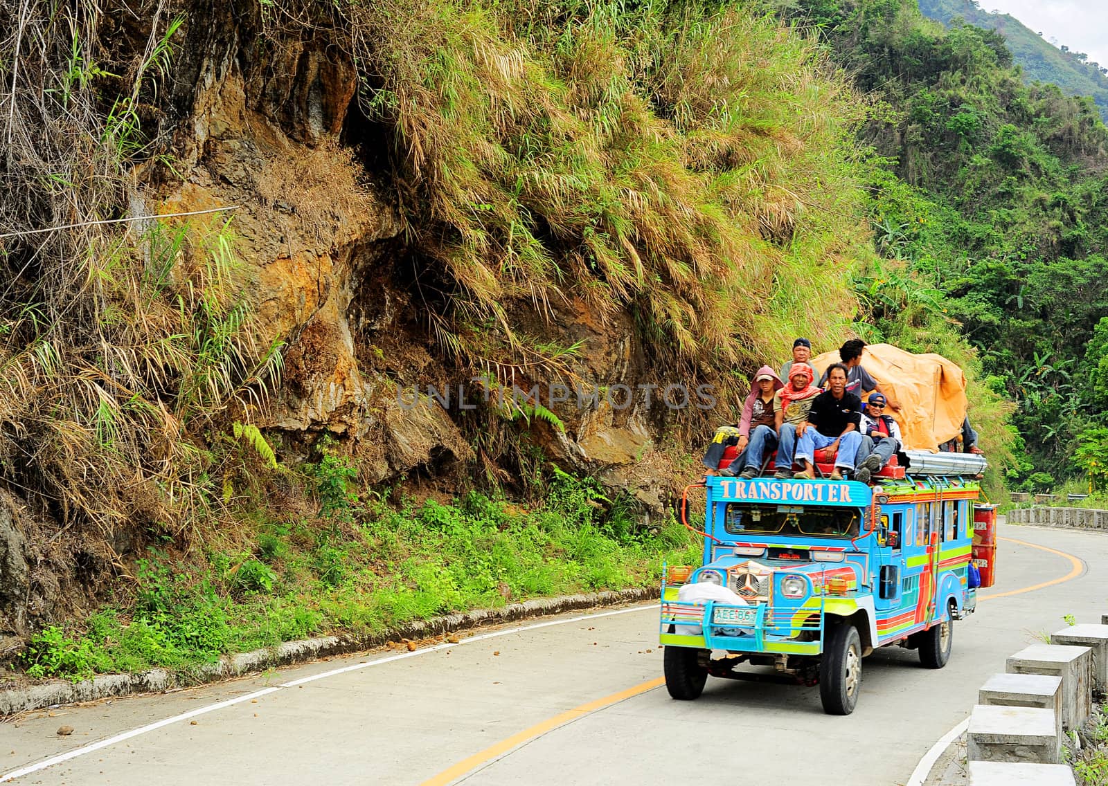Bontoc, Philippines - March 26, 2012:  Passengers sit atop a very full jeepney The jeepney found everywhere in the country. It carries between 16 to 30 passengers.