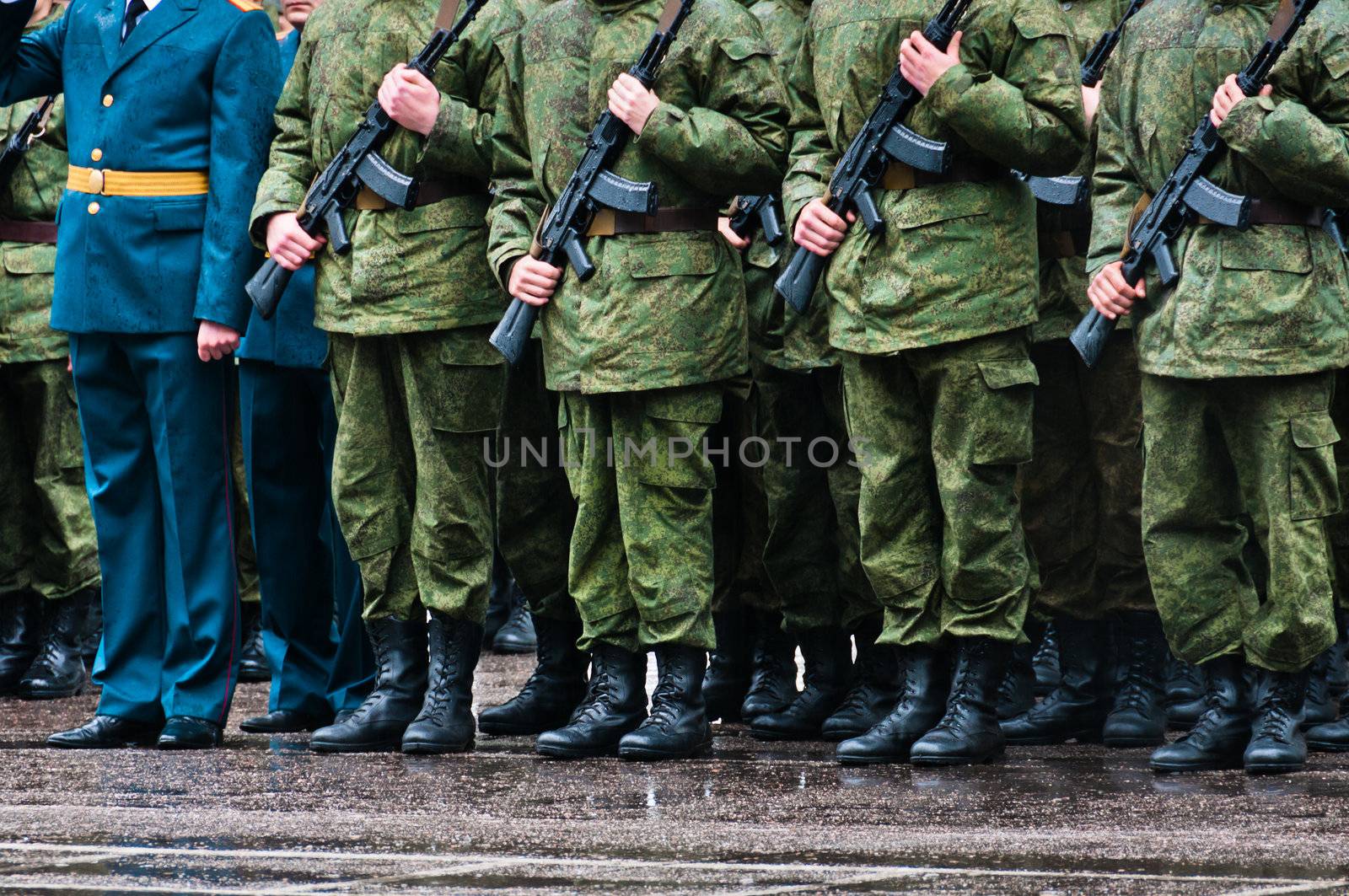Soldiers in camouflage stand in formation with officer in blue clothing