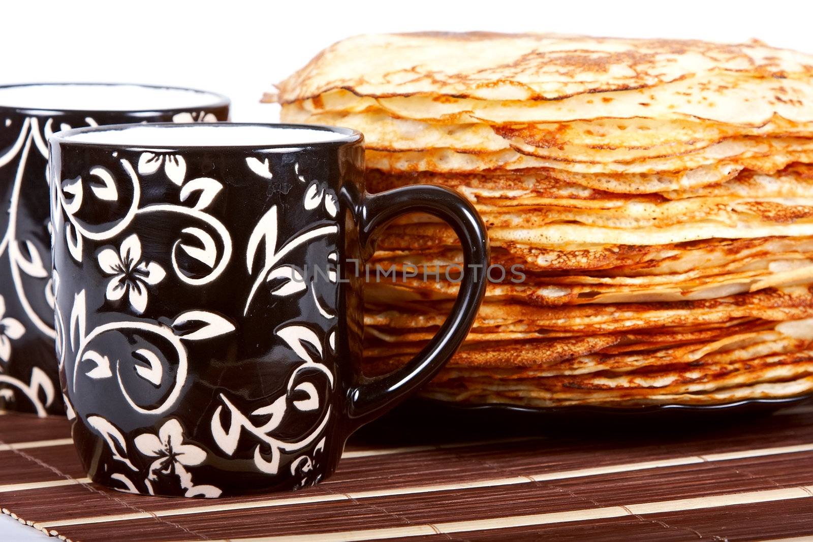 Cups with tea and a pile of pancakes on a plate