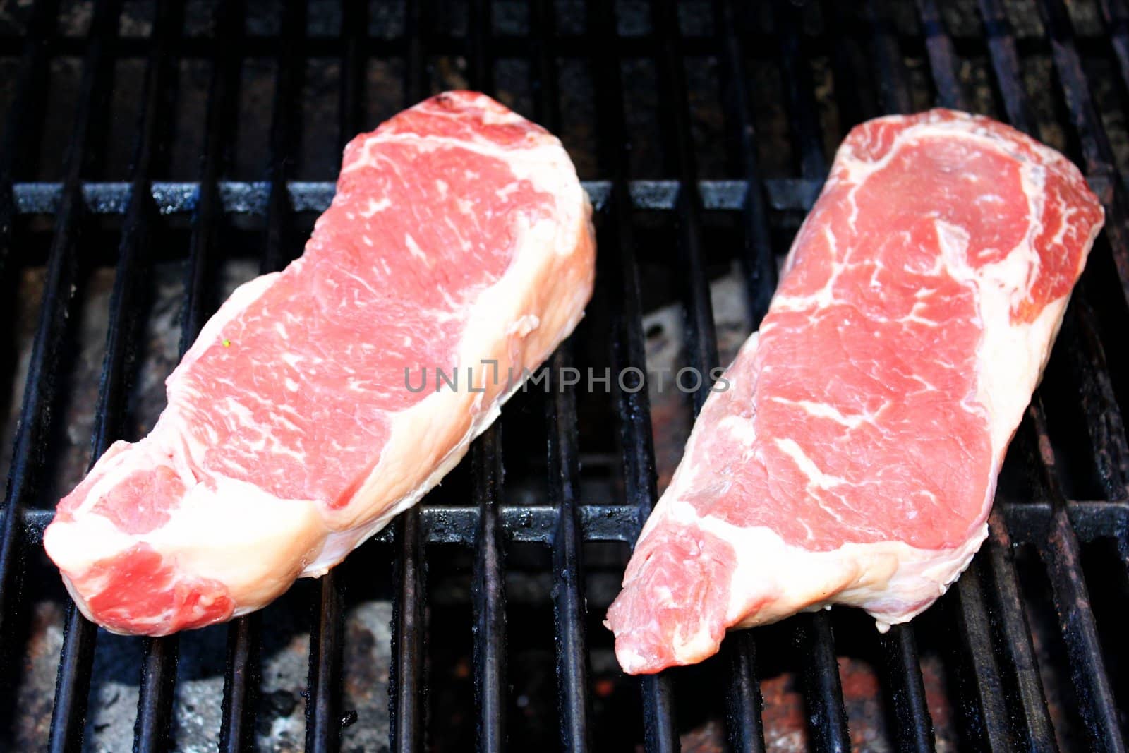 New York steak on a BBQ ready to be grilled.