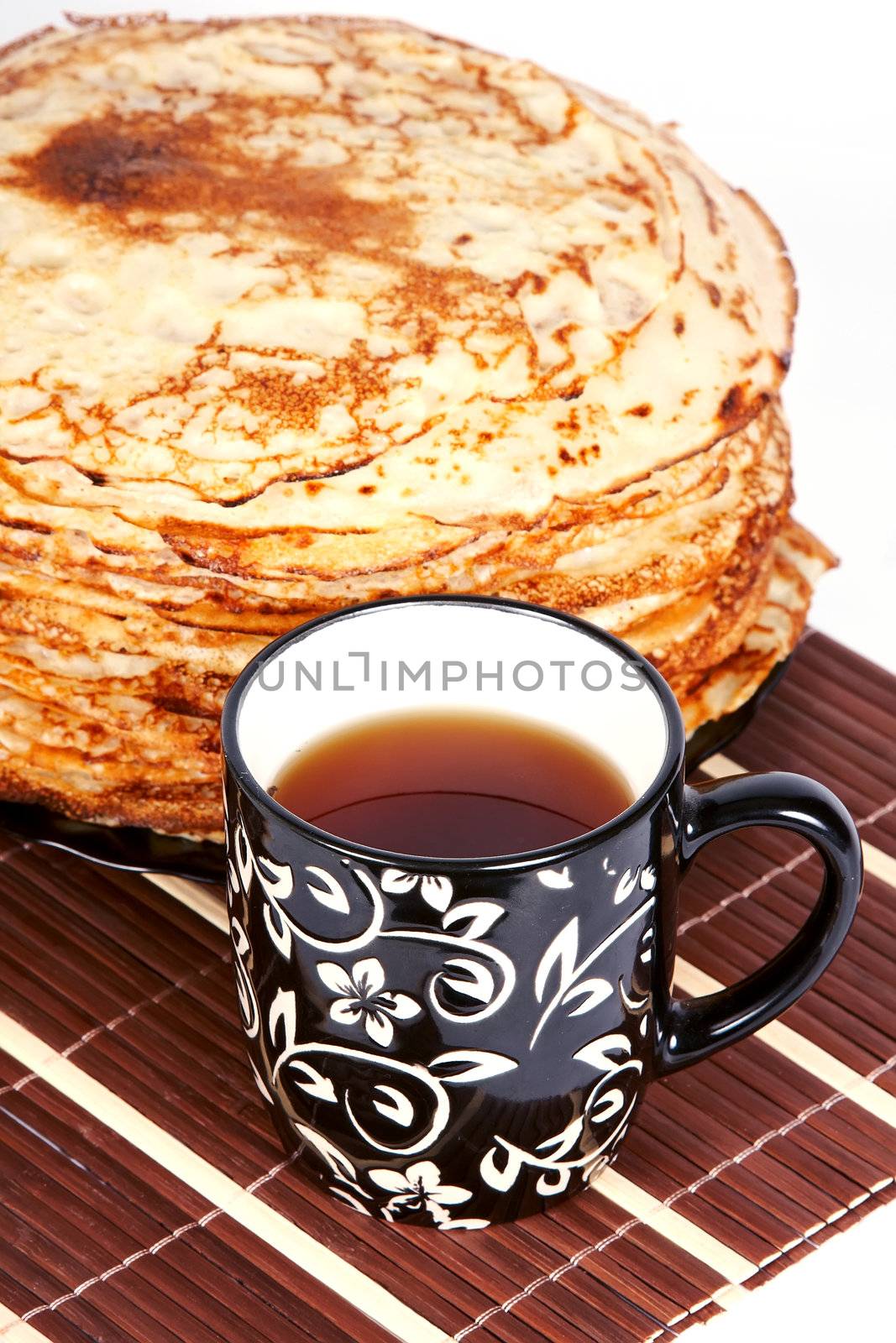 Cup with tea and a pile of pancakes on a plate