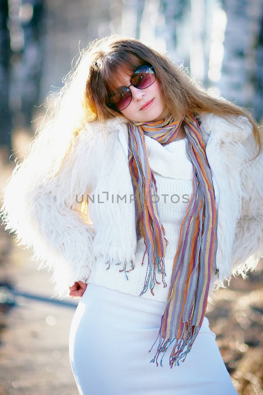 The beautiful girl in sunglasses in a white fluffy jacket
