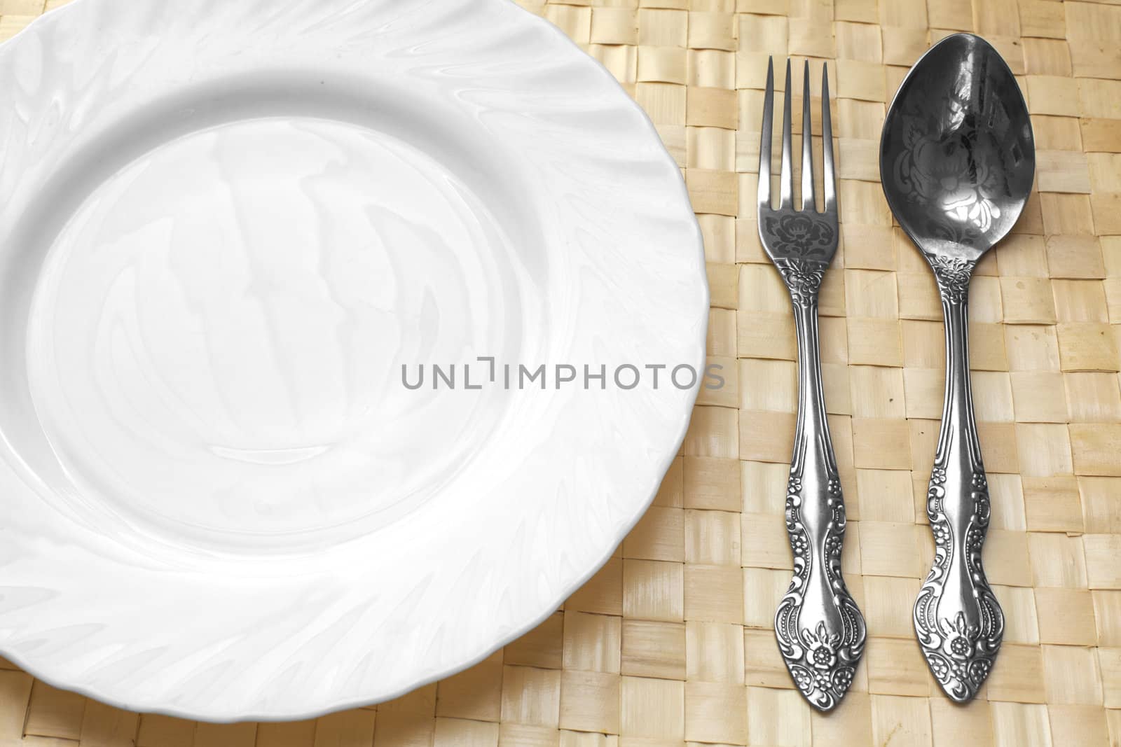 white plate, spoon and fork on a wicker napkin