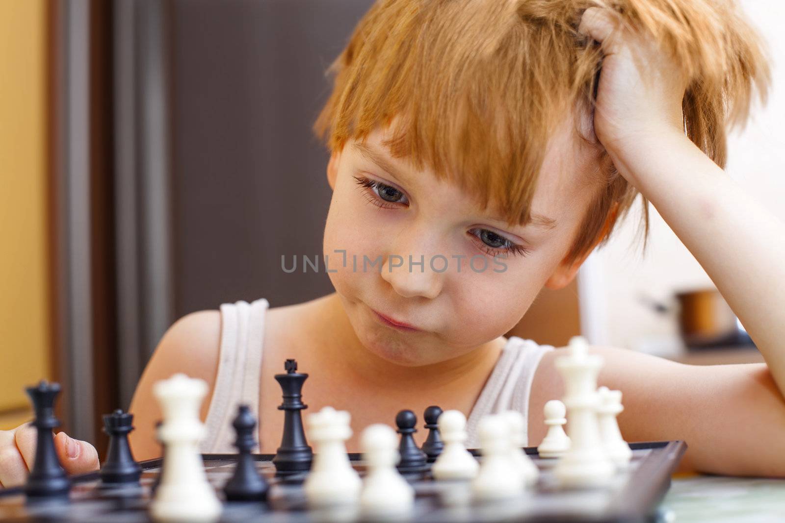 Boy playing chess, thinking how to make a move.