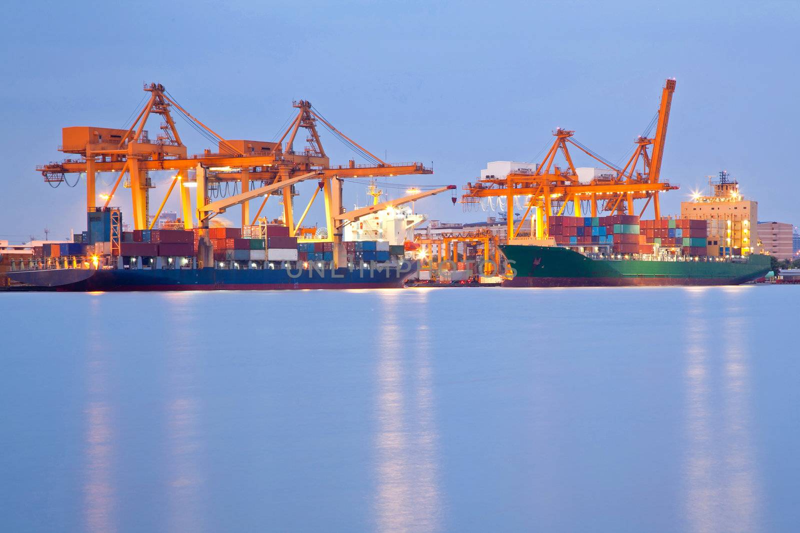 Big Container Cargo freight ship with working crane in shipyard at dusk for Logistic Import Export background