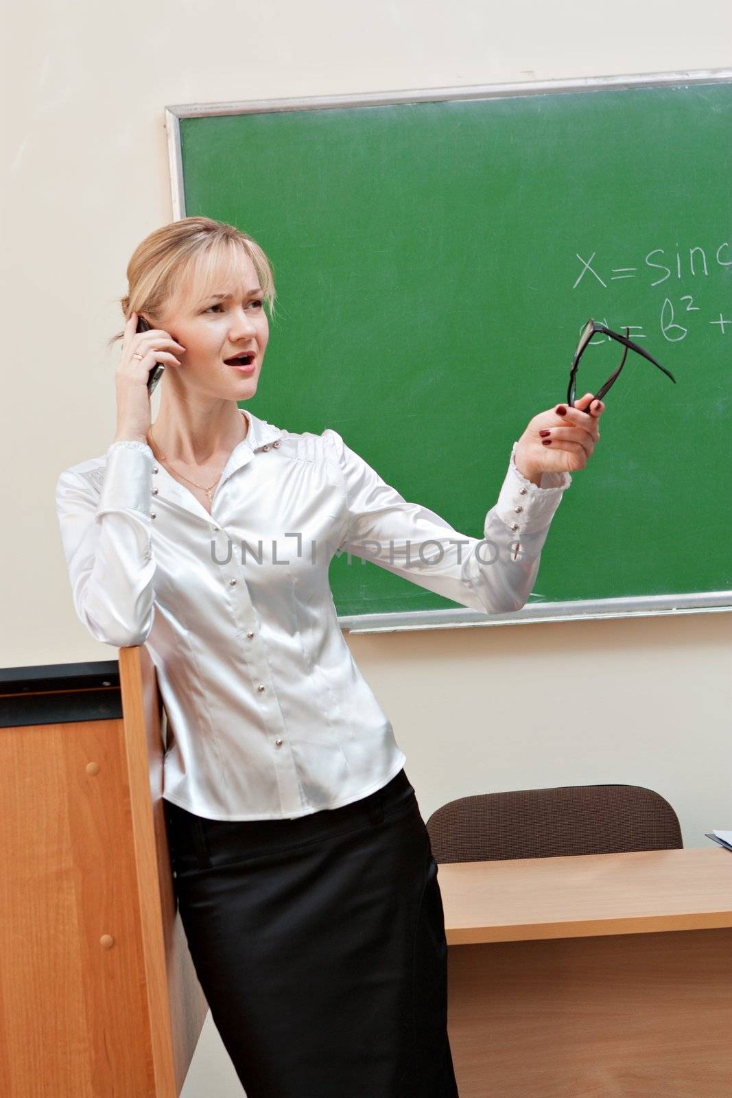 The teacher in the classroom on blackboard background.