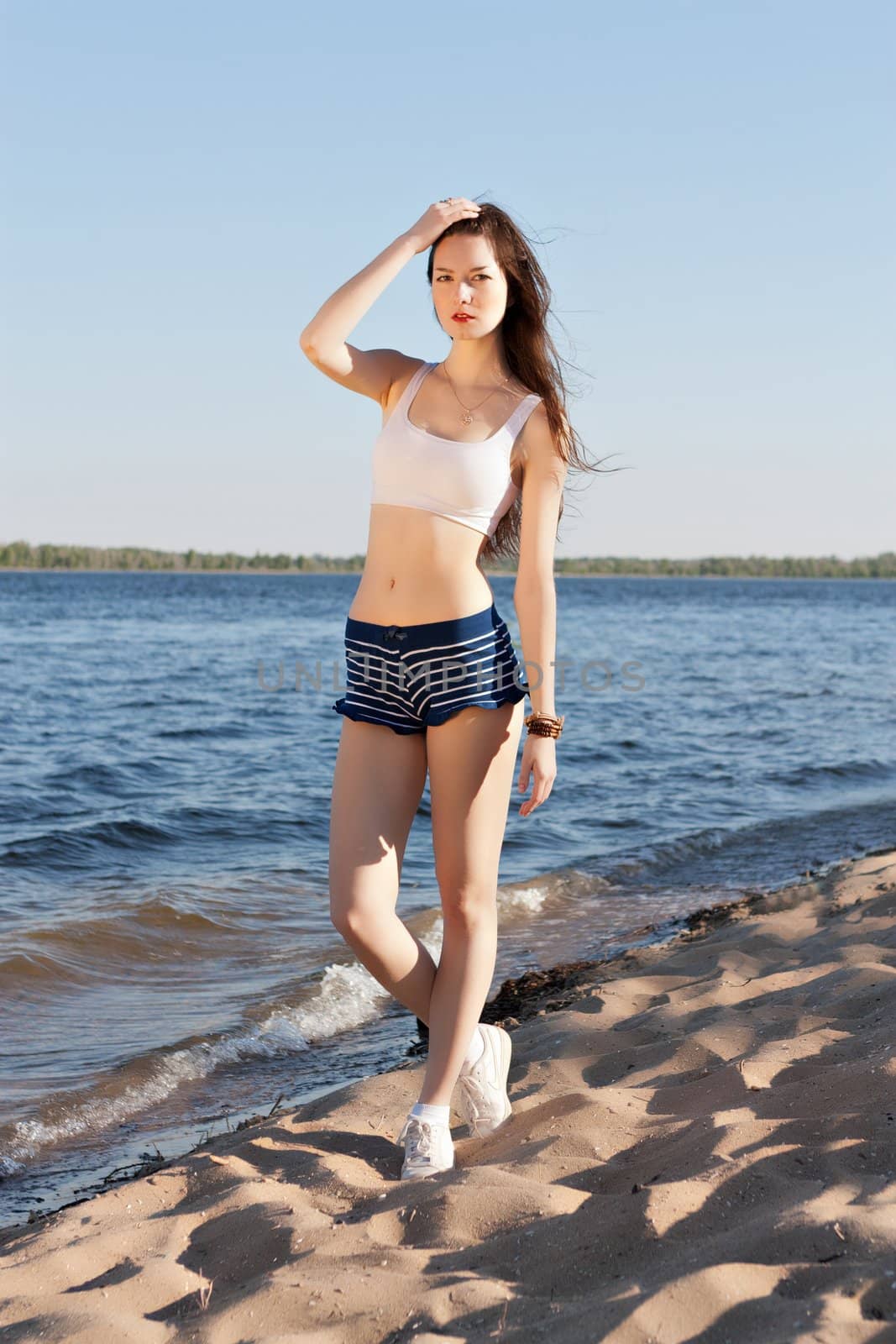 A beautiful woman on the beach in shorts.