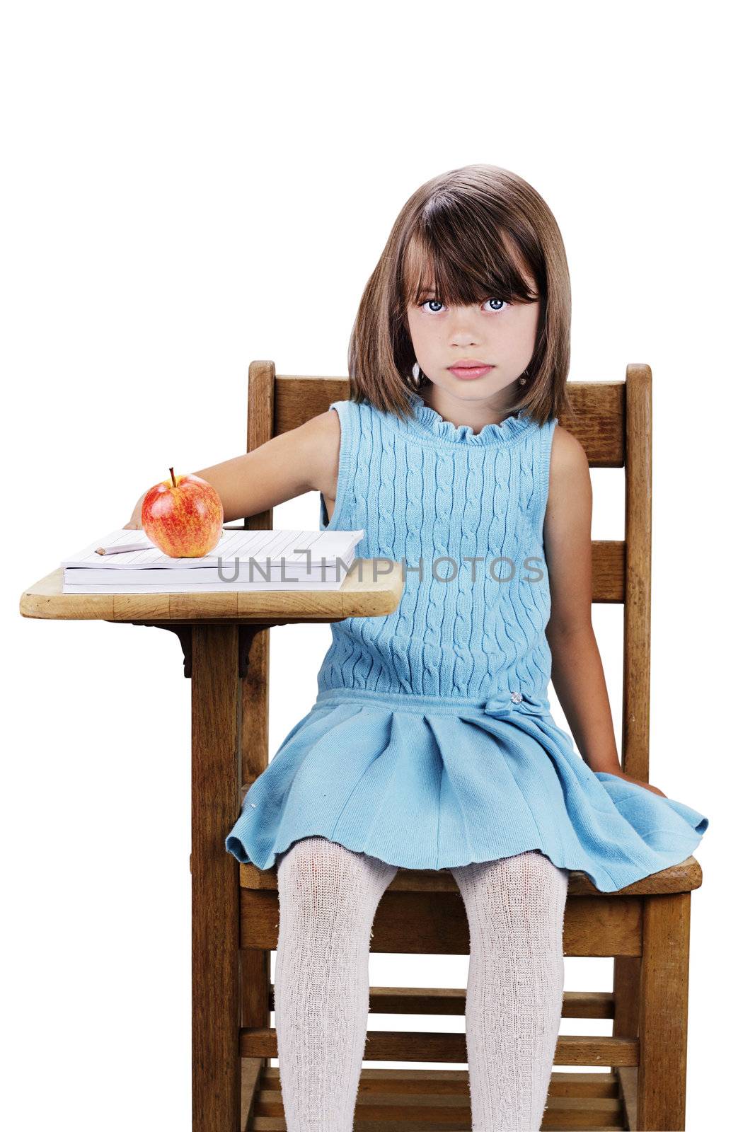 Little girl sitting at a school desk with apple and books. Isolated on a white background with clipping path included.