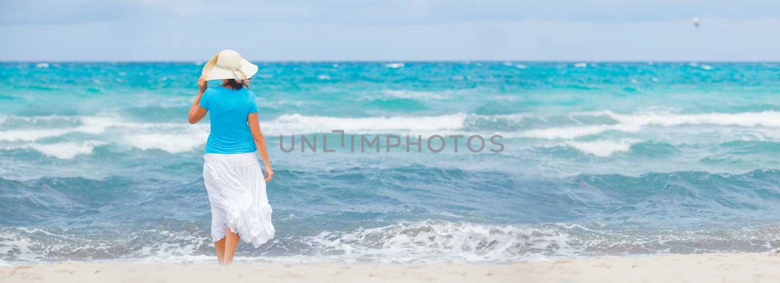 Happy beautiful woman in the beach hat looking at the sea. Panorama