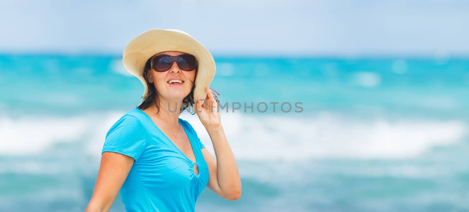 Close up portrait of happy beautiful woman in the beach hat relax near the sea