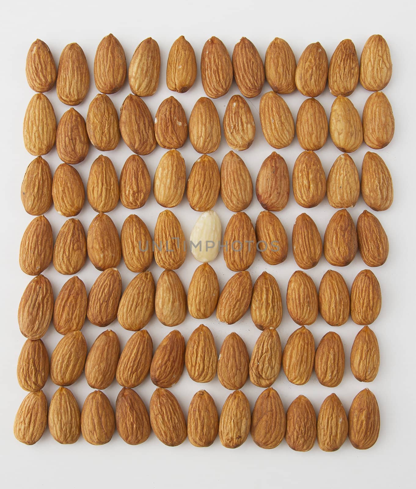 almond put in a row with one peeled almond in the middle